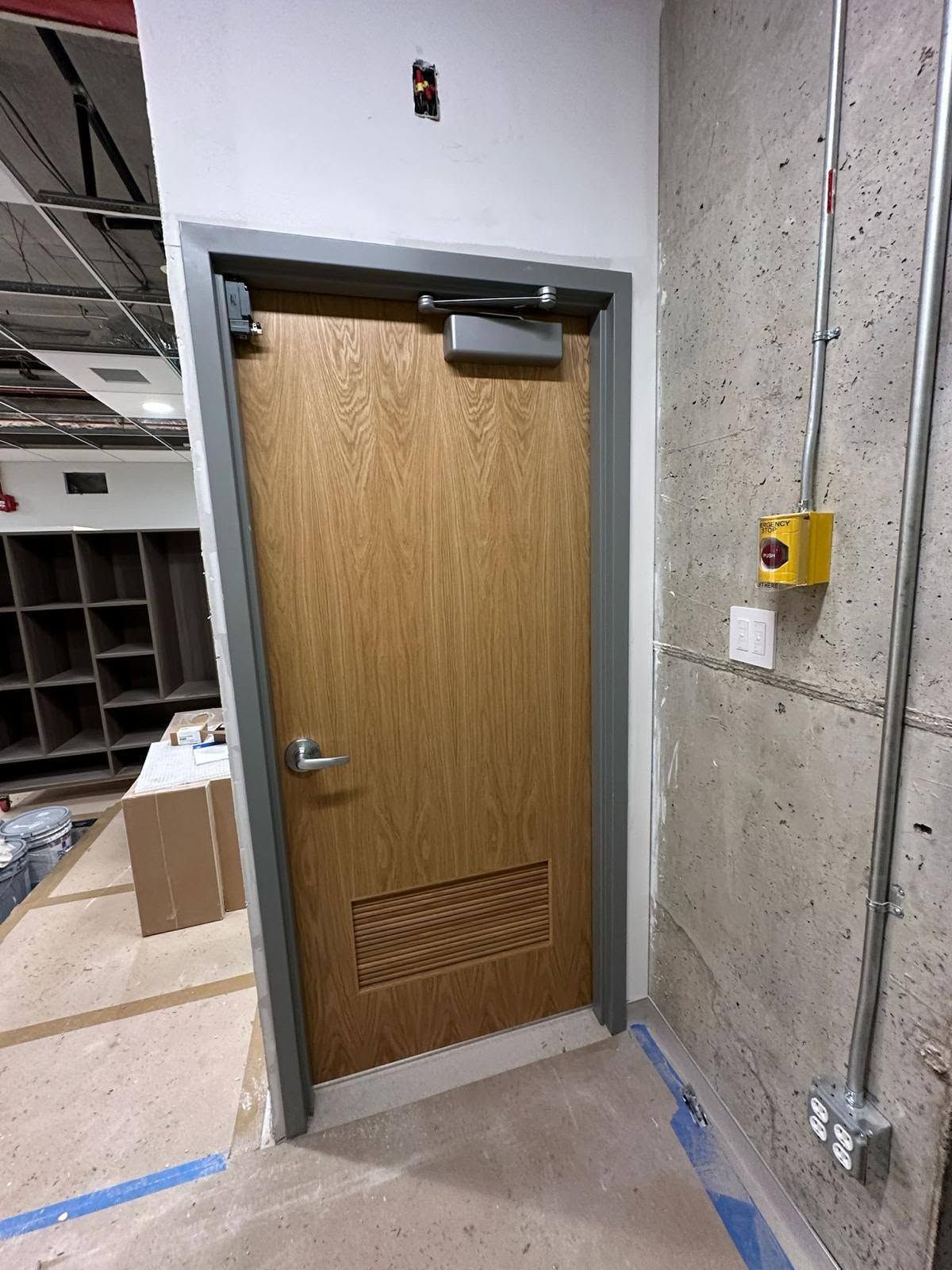 Newly installed wood door with metal frame, closer and lever handle, fitted by E&I
